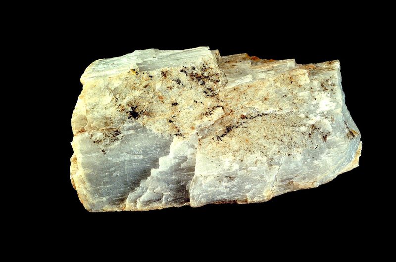 A pale spodumene ore specimen on a black background